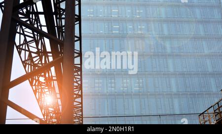 Edificio moderno in vetro con sfondo blu cielo. Vista ad angolo basso e dettagli architettonici. Urban abstract - finestre di vetro edificio di uffici in sunligh Foto Stock