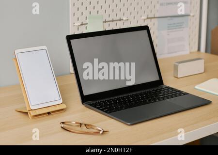 Immagine di sfondo di un notebook e di un tablet aperti con schermi bianchi sulla scrivania sul luogo di lavoro Foto Stock