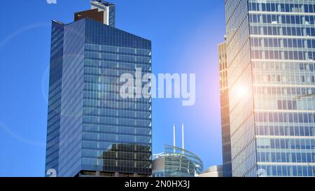 Parete a tendina blu realizzata in vetro tondo e costruzioni in acciaio sotto il cielo blu. Un frammento di un edificio. Facciate in vetro in una giornata di sole Foto Stock