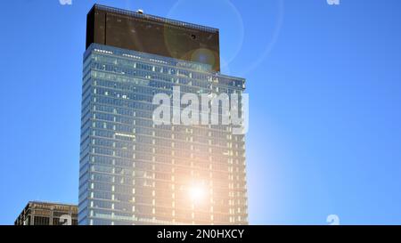 Parete a tendina blu realizzata in vetro tondo e costruzioni in acciaio sotto il cielo blu. Un frammento di un edificio. Facciate in vetro in una giornata di sole Foto Stock