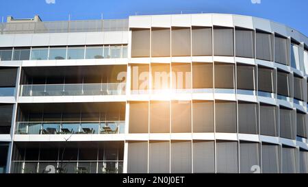 Parete a tendina blu realizzata in vetro tondo e costruzioni in acciaio sotto il cielo blu. Un frammento di un edificio. Facciate in vetro in una giornata di sole Foto Stock