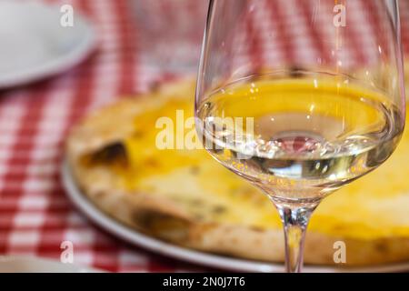 Un bicchiere di vino bianco si trova su un tavolo in un ristorante italiano, foto ravvicinata con una delicata messa a fuoco selettiva Foto Stock