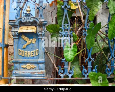 Facciata di una casa decorata con una recinzione blu e una vecchia cassetta postale con una colomba e una busta dorata Foto Stock