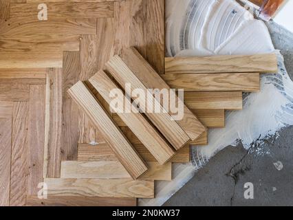 Vista dall'alto di pannelli in parquet che si installano in una disposizione a spina di pesce su colla, concetto di pavimentazione domestica Foto Stock