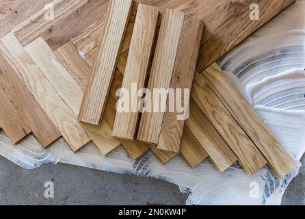 Vista dall'alto di pannelli in parquet che si installano in una disposizione a spina di pesce su colla, concetto di pavimentazione domestica Foto Stock