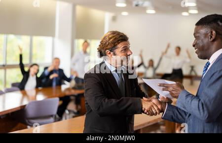 Uomini d'affari positivi handshaking dopo la firma del contratto Foto Stock