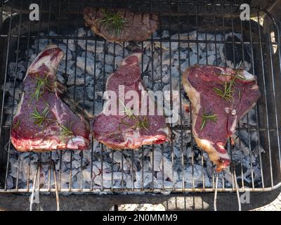 Quattro bistecche di manzo grigliate al barbecue e condite con rosmarino Foto Stock