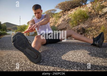 Un atleta si allunga dopo un allenamento toccando i piedi con le mani Foto Stock