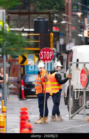 Ufficiale di controllo del traffico donna in possesso di un segnale di stop rosso indossare dpi, cantiere Melbourne città Australia. Foto Stock