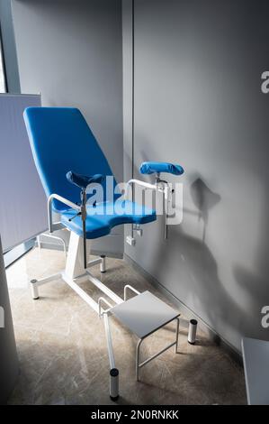 Sedia ginecologica blu vuota nell'ufficio del ginecologo. Foto Stock