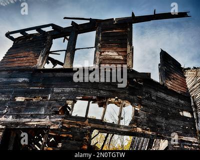 Alcune travi bruciate e una facciata in legno sono tutti che rimangono di una casa distrutta da arson. Foto Stock