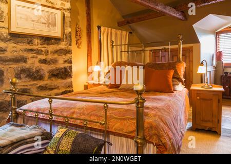 Camera da letto principale con antico letto queen size in ottone, comodini in legno al piano superiore all'interno della vecchia casa Canadiana stile cottage del 1850 circa. Foto Stock