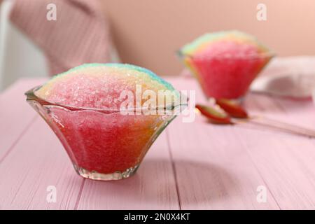 Ghiaccio da barba arcobaleno in ciotole di vetro da dessert su tavolo di legno rosa all'interno Foto Stock