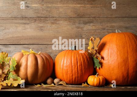 Zucche mature, noci e foglie autunnali su tavola di legno. Buon giorno del Ringraziamento Foto Stock