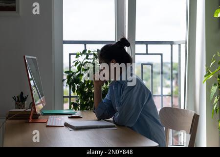 Un imprenditore asiatico di donna messo a fuoco autosufficiente siede alla scrivania con il computer in ufficio domestico Foto Stock