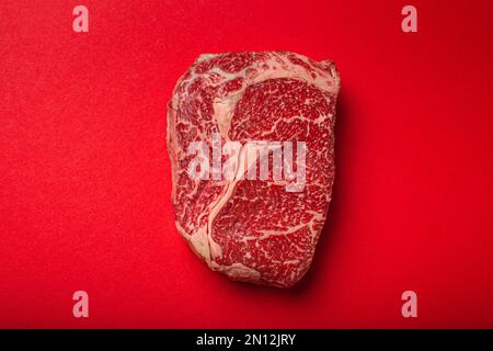 Carne cruda fresca cruda di manzo bistecca di prima qualità Ribeye su sfondo rosso pulito dall'alto, beefsteak concetto banner minimalismo Foto Stock