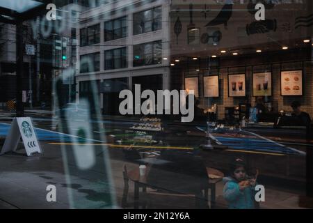 Un cliente ha visto mangiare cibo all'interno di Starbucks Seattle Downtown con un cartello che mostra il logo Starbucks sulla strada. Starbucks ha annunciato la chiusura del suo negozio situato a Broadway e Denny a Capitol Hill, Seattle, a causa di "incidenti di sicurezza". La posizione, che è stato il primo negozio Starbucks a unionizzare a Seattle, ha suscitato polemiche tra i dipendenti che affermano che la chiusura è il risultato di una tattica di Unione-busting. Workers United, il sindacato dei dipendenti, sostiene che la chiusura è prevista per l'anniversario della formazione del sindacato l'anno scorso, e il negozio Capitol Hill Foto Stock
