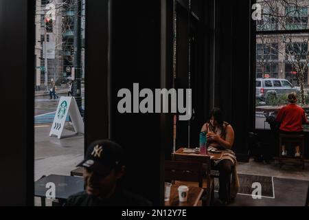 Un cliente ha visto mangiare cibo all'interno di Starbucks Seattle Downtown con un cartello che mostra il logo Starbucks sulla strada. Starbucks ha annunciato la chiusura del suo negozio situato a Broadway e Denny a Capitol Hill, Seattle, a causa di "incidenti di sicurezza". La posizione, che è stato il primo negozio Starbucks a unionizzare a Seattle, ha suscitato polemiche tra i dipendenti che affermano che la chiusura è il risultato di una tattica di Unione-busting. Workers United, il sindacato dei dipendenti, sostiene che la chiusura è prevista per l'anniversario della formazione del sindacato l'anno scorso, e il negozio Capitol Hill Foto Stock