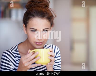 Rilassatevi con una cuppa. Ritratto di una giovane donna attraente godendo una tazza di caffè a casa. Foto Stock