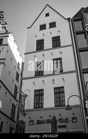 Un'immagine in scala di grigi di un edificio lungo una strada a Colonia, Germania - fotografia di strada Foto Stock