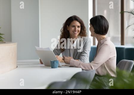 Due colleghi aziendali diversi e sicuri che parlano donne sul posto di lavoro Foto Stock
