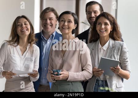 Felice gruppo di diversi dipendenti che si riuniscono in ufficio Foto Stock