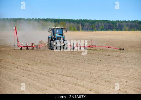 Trattore Field Farmer aratura Terra cielo nuvole Foresta raccolto di polvere semi coltivazione campo agricolo attrezzatura prato spazio soleggiato giorno verde erba estate Foto Stock