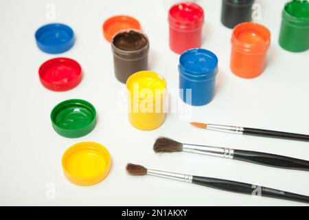 gouache vasi di vernice con pennelli su bianco. hobby pittura posto di lavoro-creatività disegno insegnamento a casa Foto Stock