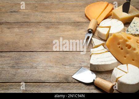 Set di diversi formaggi e coltelli specializzati e forchetta su tavola in legno. Spazio per il testo Foto Stock
