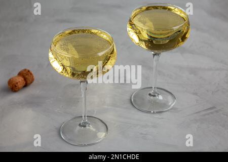 Champagne frizzante in una coppa di vetro su sfondo grigio, vista laterale. Foto Stock