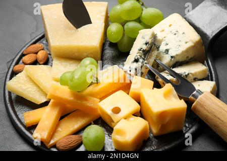 Piatto di formaggi con coltello specializzato e forchetta su tavolo nero, vista in primo piano Foto Stock