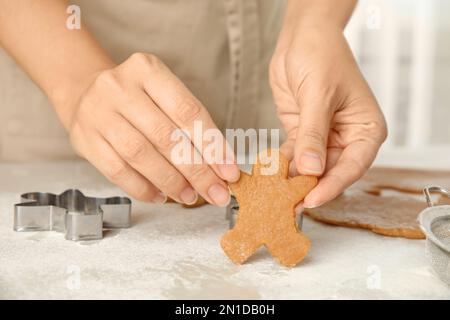 Donna che tiene biscotto di Natale a tavola leggera, primo piano Foto Stock