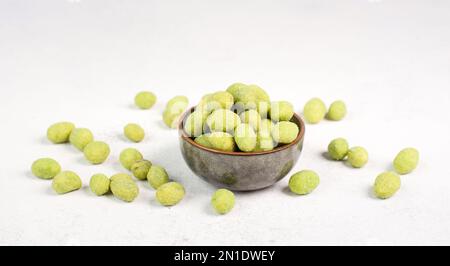 Mucchio di arachidi verdi rivestite con wasabi in una ciotola, snack piccante, cibo orientale Foto Stock