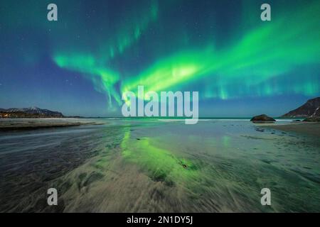 Cielo stellato notturno con aurora boreale (Aurora boreale) riflessa nel mare freddo, spiaggia di Skagsanden, Ramberg, Nordland, Isole Lofoten, Norvegia Foto Stock