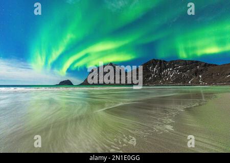 Onde che si schiantano sulla spiaggia di Haukland, sotto l'aurora boreale (Aurora borealis), Leknes, contea di Nordland, Isole Lofoten, Norvegia, Scandinavia Foto Stock