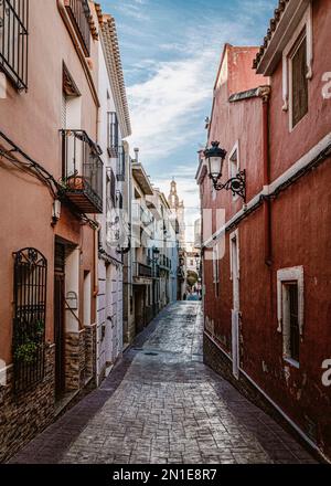 Vecchia strada nella città di Relleu con la sua chiesa storica sullo sfondo. Situato nella provincia di Alicante, Spagna Foto Stock