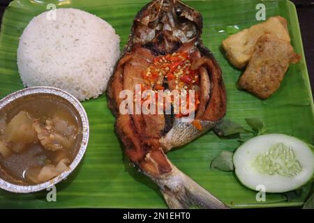 Pesce fritto con sambal, verdure dall'Indonesia con riso bianco isolato su una foglia di banana Foto Stock