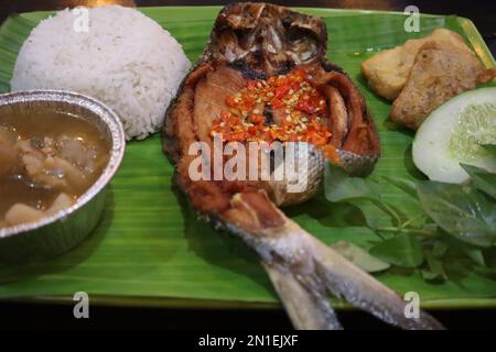 Pesce fritto con sambal, verdure dall'Indonesia con riso bianco isolato su una foglia di banana Foto Stock