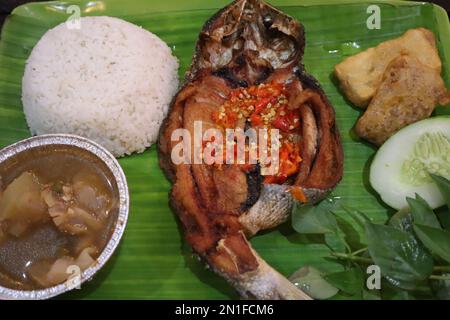 Pesce fritto con sambal, verdure dall'Indonesia con riso bianco isolato su una foglia di banana Foto Stock