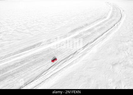 Vista aerea dell'automobile che viaggia su una strada ghiacciata vuota, sul mare ghiacciato, Lulea, Norrbotten County, Lapponia, Svezia, Scandinavia, Europa Foto Stock