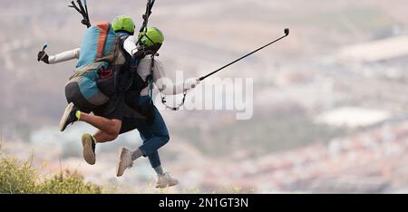 Volare parapendio tandem sopra la città in una giornata di sole Foto Stock