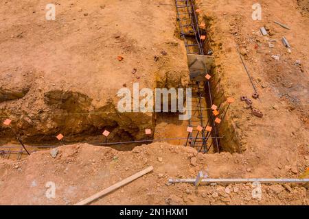 Costruzione di cemento striscia fondazione per la nuova casa così come la creazione di trincee sotto casa per calcestruzzo da versare Foto Stock