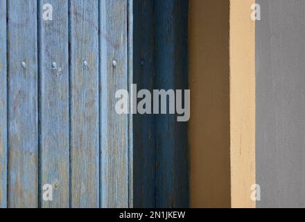 Vecchia casa rurale persiane in legno blu chiaro con finiture bianche su una parete di stucco veneziano. Foto Stock