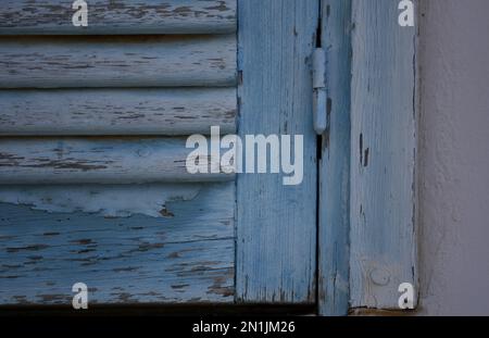 Vecchia casa rurale persiane in legno blu chiaro con finiture bianche su una parete di stucco veneziano. Foto Stock