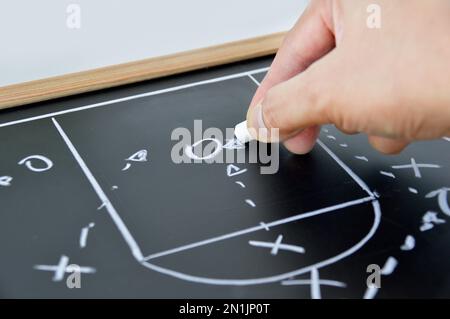 mano di un allenatore di basket che disegna una tattica di gioco con gesso bianco sulla lavagna Foto Stock