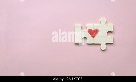 Vista dall'alto di due pezzi di un puzzle che forma un cuore su uno sfondo rosa con spazio di copia. Concetto di amore. Foto Stock