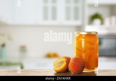 Vasetto con pesche sottaceto su tavolo in legno in cucina. Spazio per il testo Foto Stock