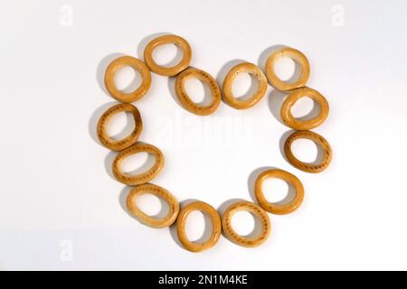 Piatti tradizionali russi per il tè, essiccazione rotonda o ovale, isolati su sfondo bianco a forma di cuore. Bagel essiccati al forno. Dessert. Foto Stock
