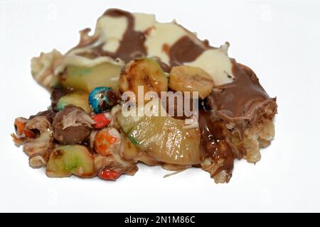 Miscela di cioccolato con biscotti e diversi tipi di pezzi di cioccolato e crema con ananas fresco e pezzi di banane sulla parte superiore su una torta di pasta Foto Stock