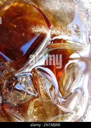 Primo piano dei riflessi e delle texture di alcuni cubetti di ghiaccio su una bevanda analcolica Foto Stock